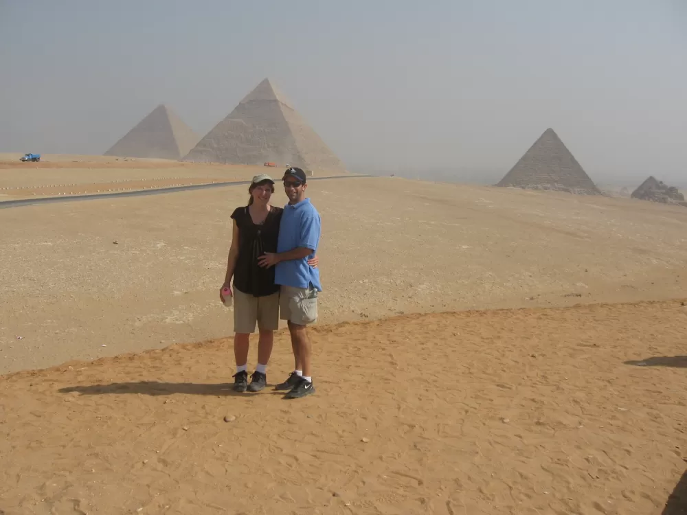 A couple poses in front of the pyramids.