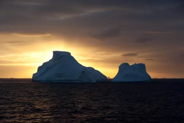 The sun sets over remote icebergs in Antarctica
