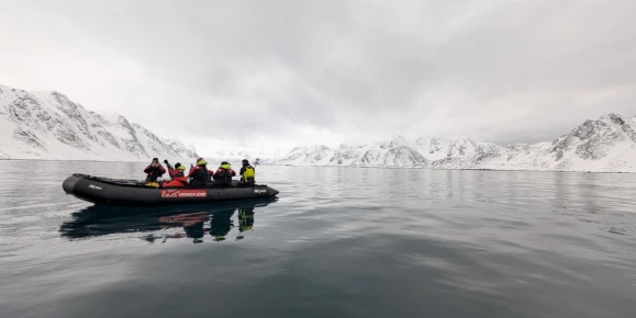 A group of travelers riding a zodiac in the Arctic.