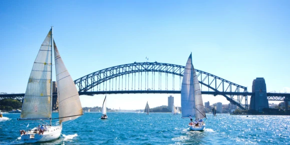 Sailboats on a sunny day at Sydney Harbor, Australia. Iconic Sydney Harbor Bridge in the background.