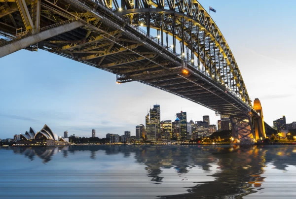 Dramatic widescreen panoramic image of the city of Sydney at sunset with bridge in foreground