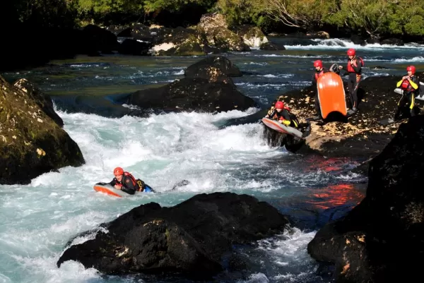 Travelers on individual rafts going down the rapids.