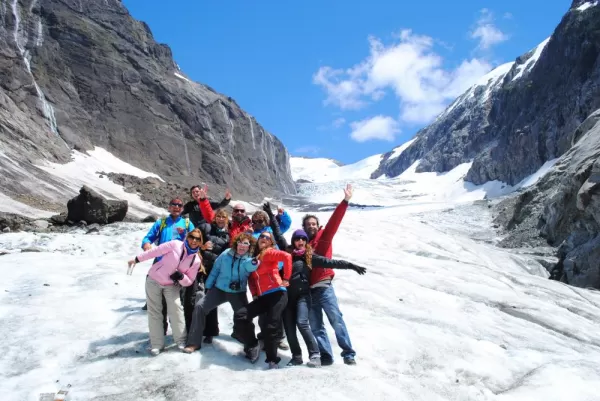 Travelers pose at the base of a glacier.