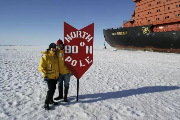Travelers standing next to the North Pole.