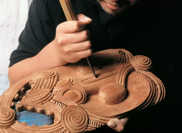 A local craftsman carves a Maori design